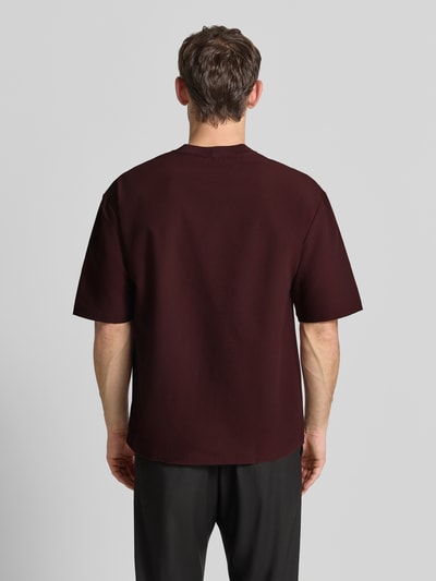 Männermodel trägt T-Shirt mit Strukturmuster und Rundhalsausschnitt von Emporio Armani in Dunkelrot, Material-Mix, Rückenansicht, Ganzkörperansicht Rückansicht.