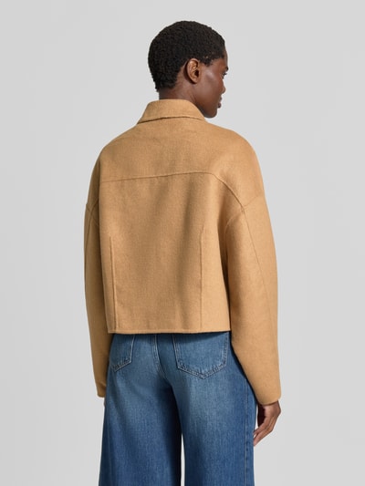 Frauenmodel trägt Regular Fit Blouson mit integriertem Schal am Kragen Modell 'C_Cafrina' von BOSS aus der BOSS Orange Kollektion in Beige, strukturierte Oberfläche, kombiniert mit blauer Jeans, Ganzkörperansicht Rückansicht.