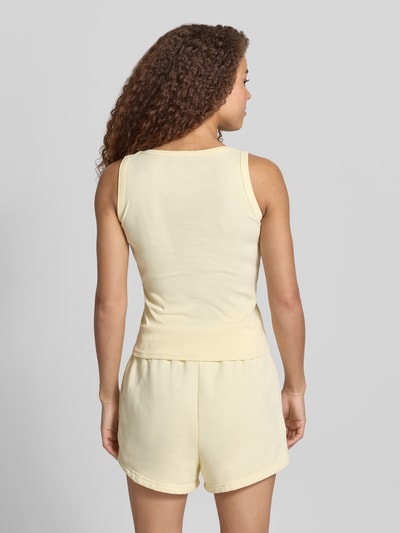 Frauenmodel trägt Tanktop mit Logo-Stitching Modell 'CESIS' von Pegador in Gelb aus Baumwoll-Mix mit Stretch-Anteil, Feinripp, Körpernaher-Schnitt, Rundhalsausschnitt, Rückenlänge bei Größe S: 52 cm, Ganzkörperansicht Rückansicht.