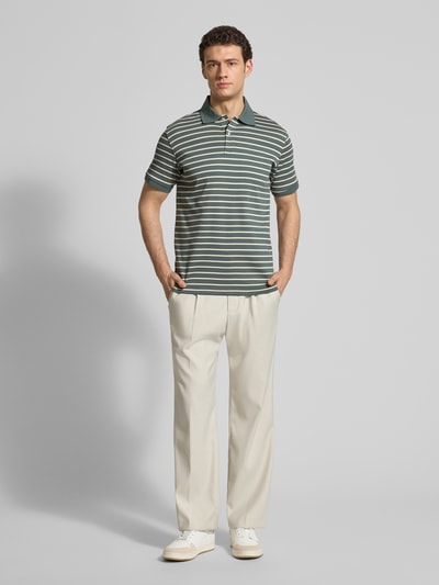 Männermodel trägt Regular Fit Poloshirt aus reiner Baumwolle Modell 'DEAN' von SELECTED HOMME in Two-Tone-Optik, gestreift, Polokragen, V-Ausschnitt, kurze Knopfleiste, Kurzarm, Ärmelabschluss gerippt, Materialverarbeitung Feinripp; Ganzkörperansicht von vorne.
