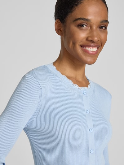 Frauenmodel trägt Slim Fit Strickjacke aus Viskose-Mix Modell 'Wonder' von Vero Moda, Optik: Unifarben, Spitzen-Besatz, Rippstrick, Nahaufnahme Oberkörper.