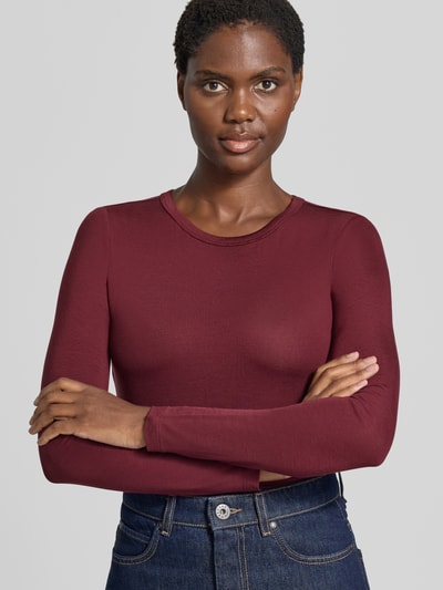 Frauenmodel trägt Slim Fit Langarmshirt aus Lyocell-Mix Modell 'ADA' von VERO MODA in Dunkelrot, glatte Textur, Nahaufnahme Oberkörper, Damen Langarmshirt von VERO MODA.