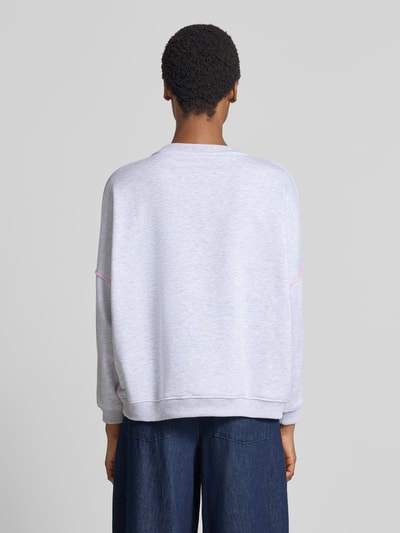 Vrouwenmodel draagt Oversized sweatshirt uit puur katoen Model 'Love' van miss goodlife, lichtgrijs met Statementprint en pailletten, ronde hals, elastische afwerkingen, oversized fit, Ganzkörperansicht Rückansicht.