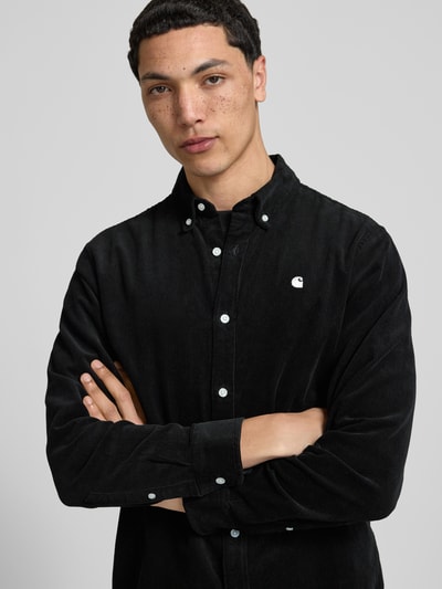 Männermodel trägt Regular Fit Freizeithemd aus Cord mit Button-Down-Kragen von Carhartt Work In Progress, schwarze Baumwolle, Nahaufnahme Oberkörper.