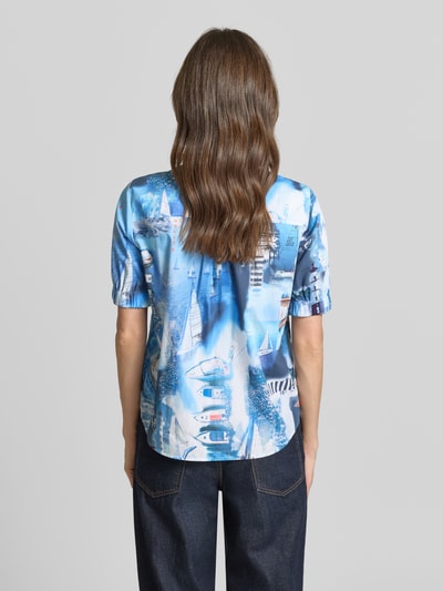 Frauenmodel trägt Regular Fit Hemdbluse mit Allover-Motiv-Print von Marc Cain aus Reine Baumwolle, kurzärmelig, Rückenlänge 62 cm, Ganzkörperansicht Rückansicht.