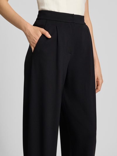 Frauenmodel trägt Bundfaltenhose mit Eingrifftaschen von Emporio Armani in Schwarz aus Viskose-Mix, Nahaufnahme Oberkörper.
