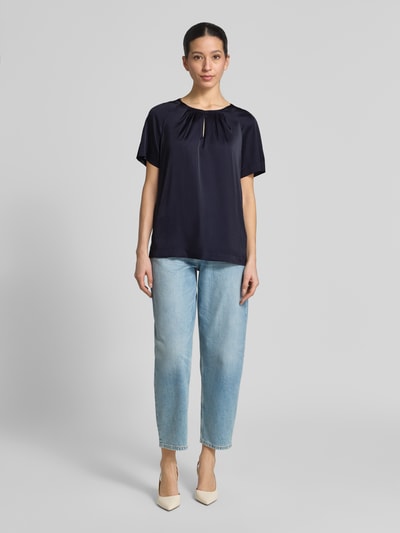 Frauenmodel trägt Blusenshirt mit Schlüsselloch-Ausschnitt von Comma aus dunkelblauem Material-Mix mit Stretch-Anteil, Regular-Fit, 1/2-Arm, Rückenlänge 60 cm, Ärmellänge 19 cm, Ganzkörperansicht von vorne.