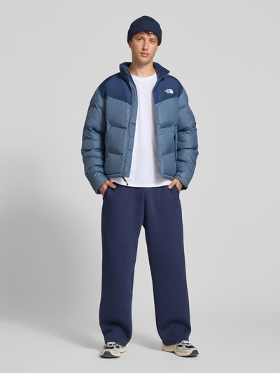 Männermodel trägt Regular Fit Jacke in Stepp-Optik Modell 'SAIKURU' von The North Face in Blau, glatte Textur, Ganzkörperansicht von vorne. Damen Jacke, Logo-Stitching, Stehkragen, Rückenlänge 65 cm, Schulterbreite 47 cm, Brustweite 56 cm, Ärmellänge 67 cm.