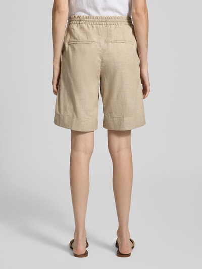 Frauenmodel trägt Bermudas mit elastischem Bund und Kordelzug Modell 'Lia Urban' von Angels aus Reine Baumwolle, Loose-Fit, beige Farbe, sichtbare seitliche Eingrifftaschen und Gesäßleistentaschen, Ganzkörperansicht Rückansicht.