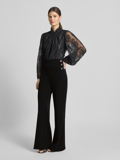 Frauenmodel trägt Flared Cut Hose mit Knöpfen von Rinascimento aus schwarzem Material-Mix mit Stretch-Anteil, Ganzkörperansicht von vorne.