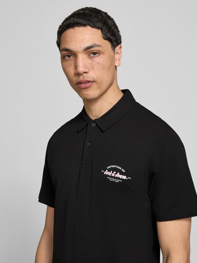 Männermodel trägt Poloshirt mit Label-Print Modell 'BRANDON' von Jack & Jones, Reine Baumwolle, Regular-Fit, Polokragen, kurze Knopfleiste, Rückenlänge bei Größe M: 71 cm, Schwarz, glatte Textur, Nahaufnahme Oberkörper.