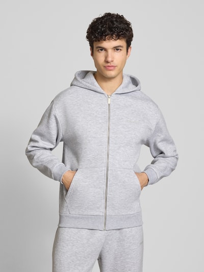 Männermodel trägt Sweatjacke mit Känguru-Tasche von REVIEW aus Baumwoll-Mix, Relaxed-Fit, Reißverschluss, graue Farbe, Ganzkörperansicht von vorne. Rückenlänge bei Größe M: 68 cm, Ärmellänge bei Größe M: 62 cm.