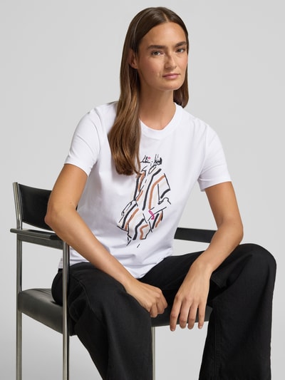 Frauenmodel trägt Regular Fit T-Shirt mit Motiv-Print von Comma, Weiß mit farbigem Motiv, elastischer Baumwoll-Mix mit Modal-Anteil, Rundhalsausschnitt, Rückenlänge bei Größe 36: 57 cm, Nahaufnahme Oberkörper.