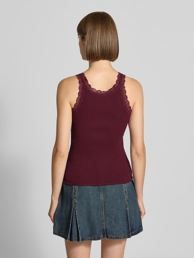 Kobieta modelka nosi top Slim Fit Tanktop aus Baumwoll-Mix model 'SARA SHARAI' od ONLY, bordowy kolor, jeansowa spódnica, faktura prążkowana, widok całej sylwetki z tyłu, damski top od ONLY