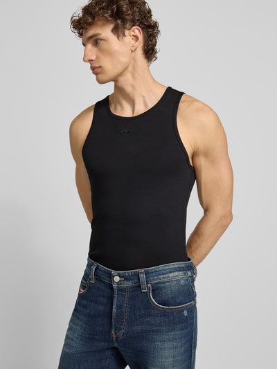 Männermodel trägt Tanktop mit Label-Stitching von Diesel in Schwarz, Baumwoll-Elasthan-Mix, Slim-Fit, gerippte Abschlüsse, Rundhalsausschnitt, Ganzkörperansicht von vorne.