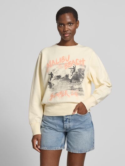 Frauenmodel trägt Relaxed Fit Sweatshirt mit Foto-Print von Anine Bing in Creme mit Statement-Print aus reiner Baumwolle, elastische Abschlüsse, Rückenlänge bei Größe S 56 cm, Ganzkörperansicht von vorne.