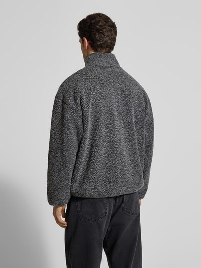 Männermodel trägt Regular Fit Jacke mit Logo-Patch von American Vintage in Grau mit Kunstfellstruktur, Stehkragen, Rückenansicht, Ganzkörperansicht.