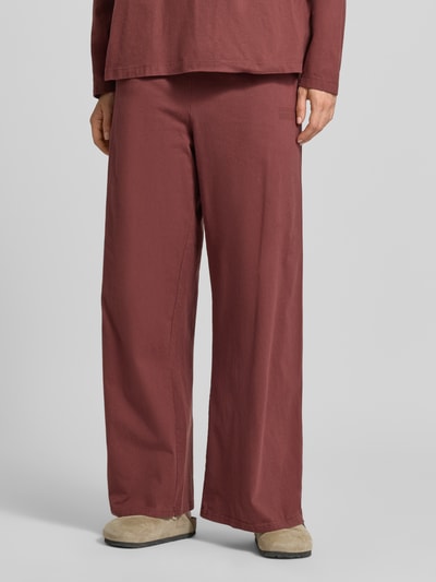 Frauenmodel trägt Wide Fit Hose aus reiner Baumwolle Modell 'GIXY' von American Vintage in Rotbraun, elastischer Bund, Nahaufnahme Unterkörper.