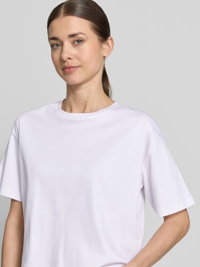 Kobiece model nosi damski t-shirt z bawełny, prosty krój, okrągły dekolt, model 'Moa Melea' od MSCH Copenhagen, długość tyłu 50 cm, zbliżenie na górną część ciała.
