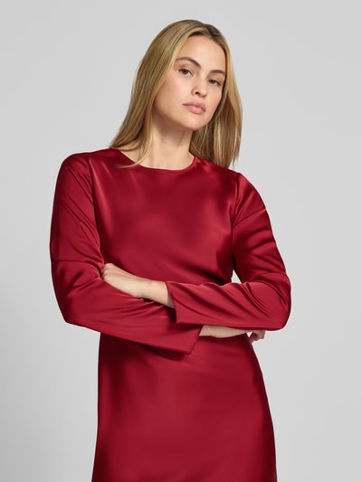 Frauenmodel trägt Midikleid aus Satin von Emporio Armani in Rot, enganliegend mit Rundhalsausschnitt und langen Ärmeln, Nahaufnahme Oberkörper.