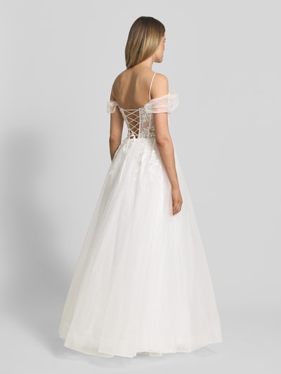 Modelka kobieca nosi Brautkleid mit floralem Stitching od Unique, biała siateczka, krój podkreślający talię, kwiatowe hafty, cekiny, cienkie ramiączka, długość tyłu w rozmiarze 36: 137 cm, szerokość w rozmiarze 36: 32 cm, widok całej sylwetki z tyłu
