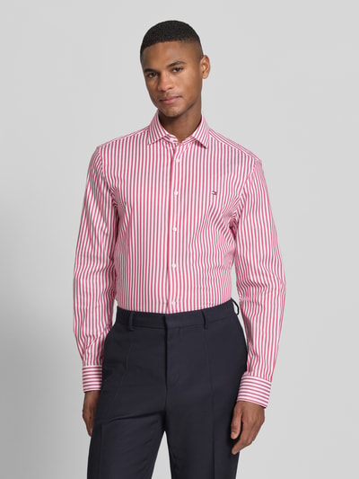 Männermodel trägt Slim Fit Businesshemd aus Baumwoll-Mix von Tommy Hilfiger mit gestreiftem Allover-Muster, Ganzkörperansicht von vorne.