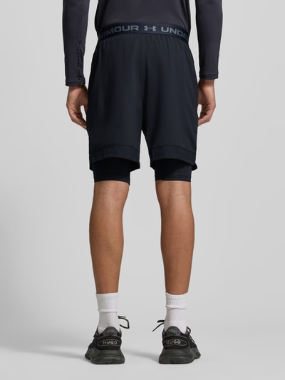 Männermodel trägt Regular Fit Shorts mit integrierten Tights Modell 'Vanish' von Under Armour, dunkle Farben, elastischer Bund, Logo-Print, Eingrifftaschen, Ganzkörperansicht Rückansicht