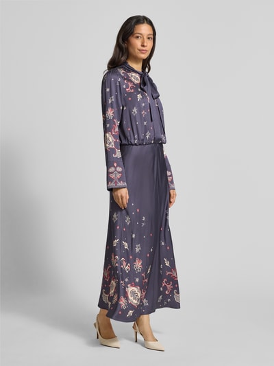 Kobiece modelka nosi Długa sukienka Maxikleid mit Schleifen-Detail od Marc Cain z wiskozy, taliowany krój, wiązany detal, długość tyłu 143 cm, szerokość klatki piersiowej 50 cm, długość rękawa 64 cm, ciemnofioletowy z wzorami, rozkloszowana spódnica, widok całej sylwetki z przodu.