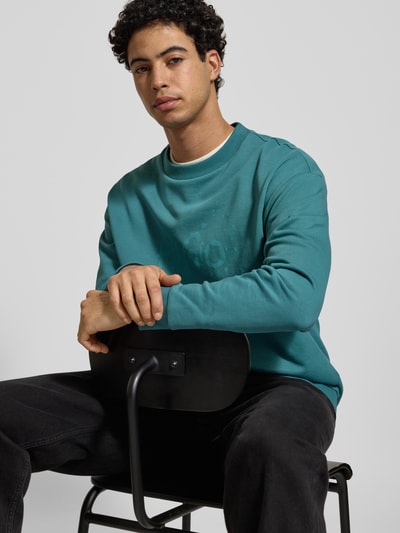 Männermodel trägt Herren Sweatshirt von Hugo Blue, Modell 'Nierofix_Crew', Farbe Blau, Optik: Unifarben, Material: reine Baumwolle, Nahaufnahme Oberkörper.