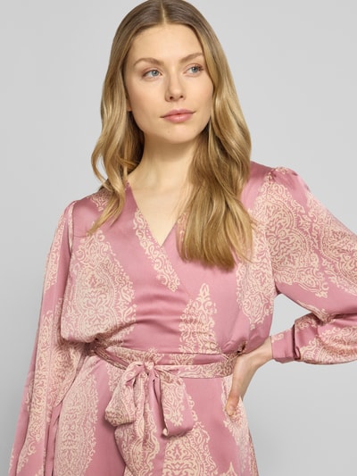 Kobiece modelka nosi Regular Fit sukienka wieczorowa z satyny model 'Bretti' od Neo Noir, wzór paisley na całej powierzchni, taliowany krój, długi rękaw, dekolt w serek, odpinana materiałowa tasiemka, kopertowy styl, jasnoróżowe i kremowe barwy, wykończone zakończenia rękawów, szerokość w rozmiarze 36: 48 cm, długość tyłu: 131 cm, długość rękawów: 63 cm, zbliżenie na górną część ciała