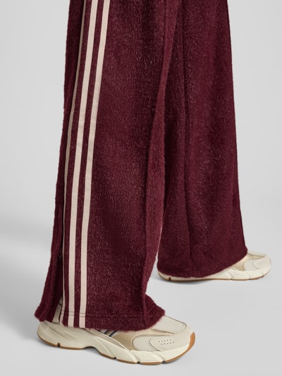 Vrouwenmodel draagt Sweatpants met elastische band van adidas Originals, los model, glittereffect, labelstitching, ritszakken, binnenbeenlengte maat S 81 cm, detailopname onderbenen.