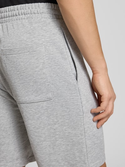 Männermodel trägt Regular Fit Shorts mit Label-Stitching von REVIEW, hellgrauer Baumwoll-Mix, elastischer Bund, Nahaufnahme Rückansicht.