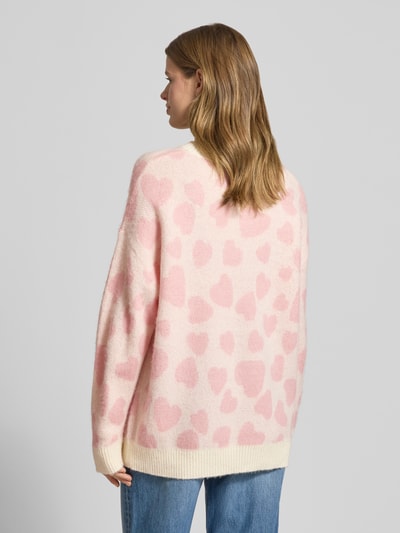 Frauenmodel trägt Relaxed Fit Strickpullover mit Woll-Mohair-Anteil Modell 'Sallyna_B' von HUGO BLUE in Creme mit rosa Allover-Muster, Stricktextur, Ganzkörperansicht Rückansicht.