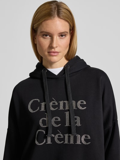 Frauenmodel trägt Oversized Hoodie mit Kapuze von miss goodlife in Schwarz, reine Baumwolle, Label-Detail, Nahaufnahme Oberkörper.