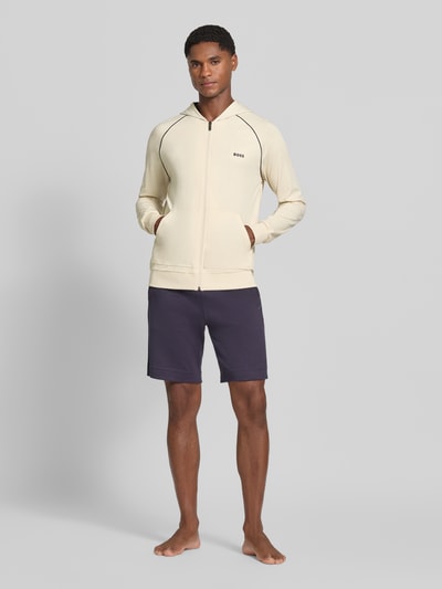 Męski model nosi Regular Fit Sweatshirt aus Baumwoll-Mix von BOSS, jasny beż i granat, proste formy, gładka faktura, Ganzkörperansicht von vorne.