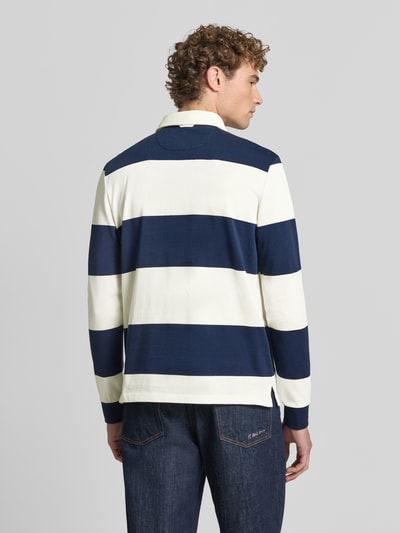 Männermodel trägt Poloshirt aus reiner Baumwolle von Christian Berg Men, breite blaue und weiße Streifen, lockere Passform, Ganzkörperansicht Rückansicht.