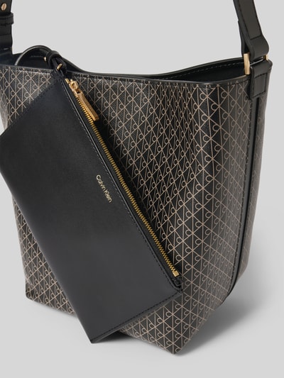 Produktfoto, Bucket Bag in Leder-Optik von CK Calvin Klein mit Allover-Logo-Print, Magnetverschluss, verstellbarem Schulterriemen, herausnehmbarer Innentasche mit Reißverschluss, Logo-Prägung, Hauptfach, Maße: Breite 27 cm, Länge 25 cm, Tiefe 12 cm, Länge Schulterriemen 50 cm, glatte und strukturierte Oberfläche in Schwarz und Gold.