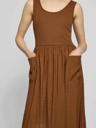 Frauenmodel trägt Midikleid mit aufgesetzten Taschen von Rich & Royal in Braun, Micromodal-Mix, taillierte Passform, Rundhalsausschnitt, Ärmelloses-Design, Ganzkörperansicht von vorne.