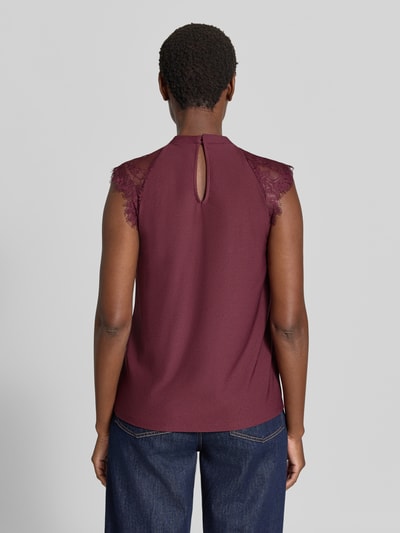 Frauenmodel trägt Regular Fit Kurzarmbluse mit semitransparenter Besatz Modell 'MILLA' von VERO MODA in Bordeaux mit Spitzenärmeln, Ganzkörperansicht Rückansicht.