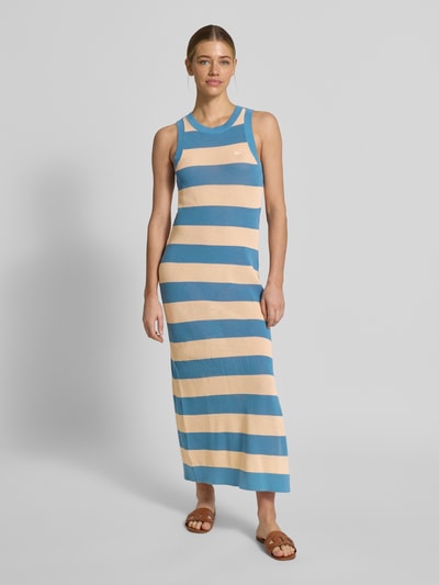 Frauenmodel trägt Enganliegendes Strickkleid aus reiner Baumwolle von Lacoste in Two-Tone-Optik, gestreift, Logo-Stitching, Midi-Länge, Strick, Ganzkörperansicht von vorne.