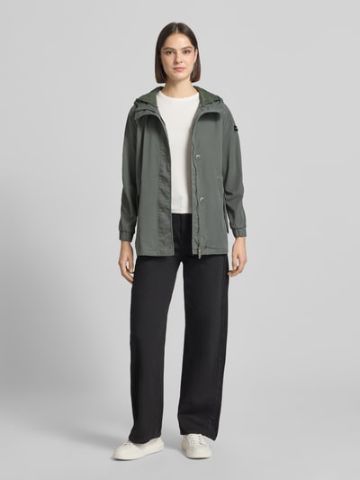 Frauenmodel trägt Regular Fit Jacke mit Logo-Detail Modell 'Dorine' von Frieda & Freddies in Grün aus Baumwoll-Mix, Kapuze, Eingrifftasche, elastische Ärmelabschlüsse, Ganzkörperansicht von vorne. Rückenlänge bei Größe 36: 72 cm, Schulterbreite 40 cm, Brustweite 57 cm, Ärmellänge 62 cm.