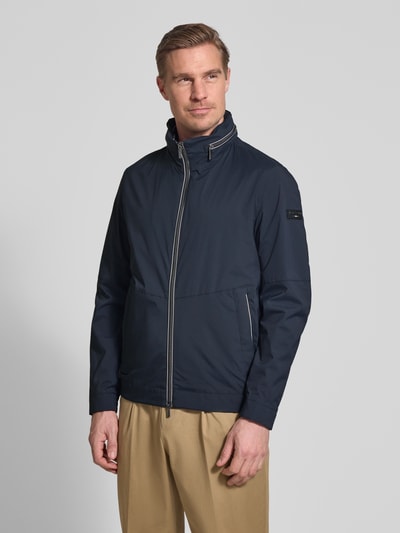 Mannelijk model draagt Regular Fit Jack met opstaande kraag van bugatti, donkerblauw, steekzakken, tweewegritssluiting, logodetail, elastische mouwboorden, capuchon, voorkant volledig zichtbaar, ganzekörperansicht von vorne.