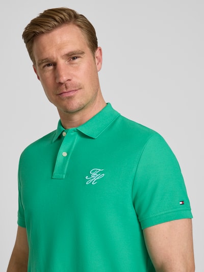 Männermodel trägt Regular Fit Poloshirt aus reiner Baumwolle von Tommy Hilfiger, Optik: Unifarben, Logo-Stitching, Kurzarm, Piqué, Nahaufnahme Oberkörper.