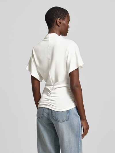 Frauenmodel trägt T-Shirt mit kurzem Stehkragen Modell 'Nupti' von My Essential Wardrobe, cremefarben, glatte Textur, Ganzkörperansicht Rückansicht. Viskose-Mix mit Stretch, körpernaher Schnitt, Rückenlänge bei Größe S 67 cm.
