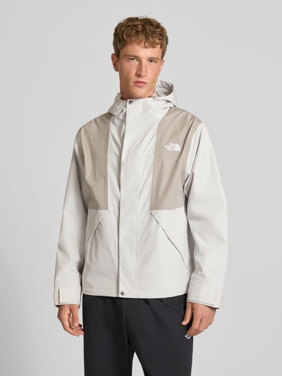 Männermodel trägt kurtka z kapturem, wyhaftowane logo, krój regular fit, model 'REIGN ON 2.0' od The North Face, jasnoszary i beżowy, Długość tyłu w rozmiarze M: 69 cm, szerokość ramion w rozmiarze M: 52 cm, szerokość klatki piersiowej w rozmiarze M: 63 cm, długość rękawów w rozmiarze M: 65 cm, zdjęcie całej sylwetki z przodu.