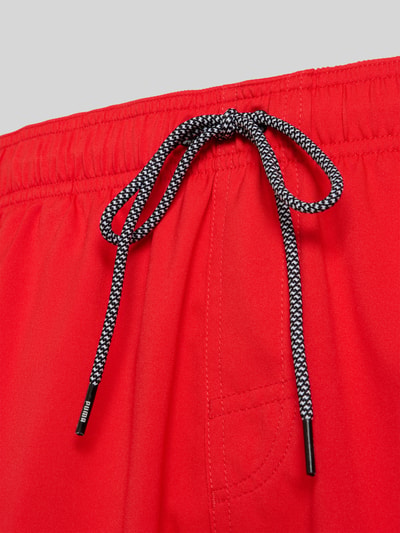 Produktfoto, Badehose mit Seitentaschen und Klettverschlusstasche hinten von PUMA in Rot, elastischer Bund, feine Textur, Nahaufnahme Oberkörper
