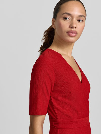 Vrouwenmodel draagt Wickelkleid met V-hals en strikceintuur van Zero in rood materiaalmix met stretch, A-lijn, midi-jurk, detailopname bovenlichaam.