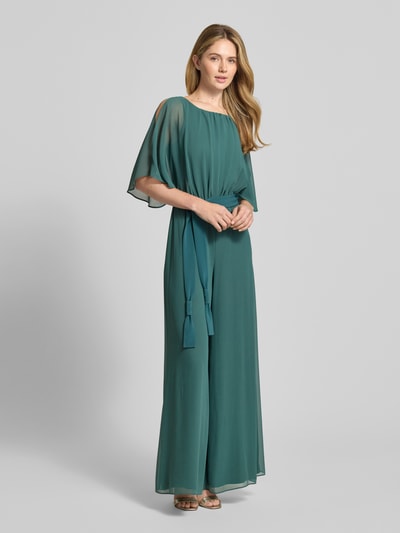 Frauenmodel trägt Jumpsuit aus fließendem Stoff mit Bindegürtel von Vera Mont in Petrol, Chiffon, weites Bein, Ganzkörperansicht von vorne. Rückenlänge bei Größe 36: 146 cm, Brustweite: 33 cm, Ärmellänge: 30 cm, Gesamtlänge: 147 cm, Innenbeinlänge: 81 cm.