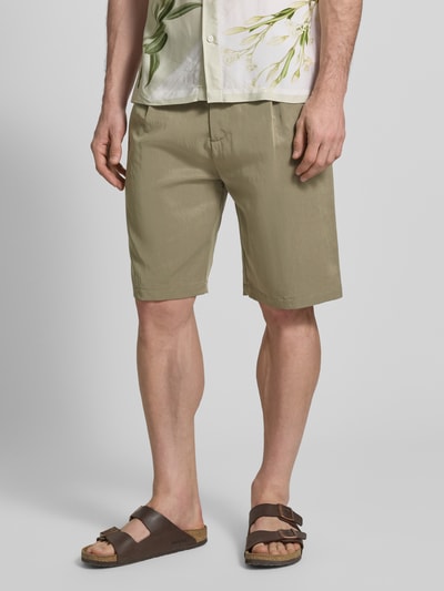 Männermodel trägt Regular Fit Shorts mit Gesäßtaschen Modell 'TAYLOR' von Guess aus Lyocell-Mix, khakifarben, Ganzkörperansicht von vorne. Bundweite bei Größe 32: 46 cm, Innenbeinlänge bei Größe 32: 28 cm, Knopf- und Reißverschluss.