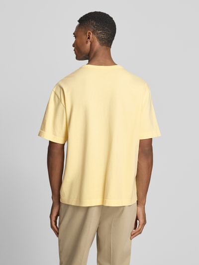 Männermodel trägt Cropped T-Shirt mit Rundhalsausschnitt von GAP in Hellgelb, reine Baumwolle, lockere Passform, Ganzkörperansicht Rückansicht.